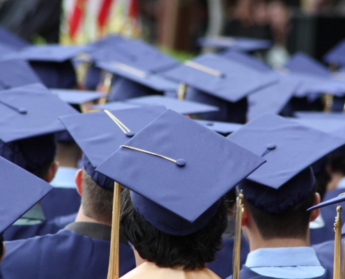Back view of several students at graduation wearing graduation caps